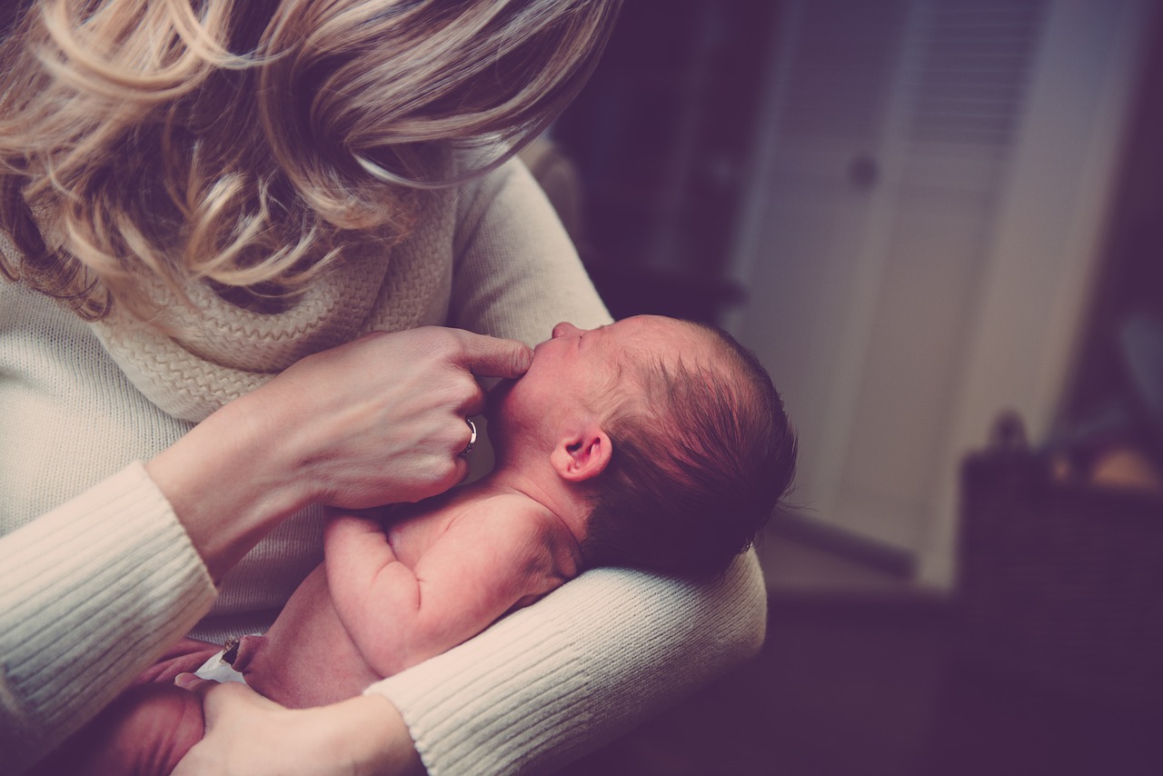 Mãe segurando recém-nascido no colo com carinho em um ambiente acolhedor